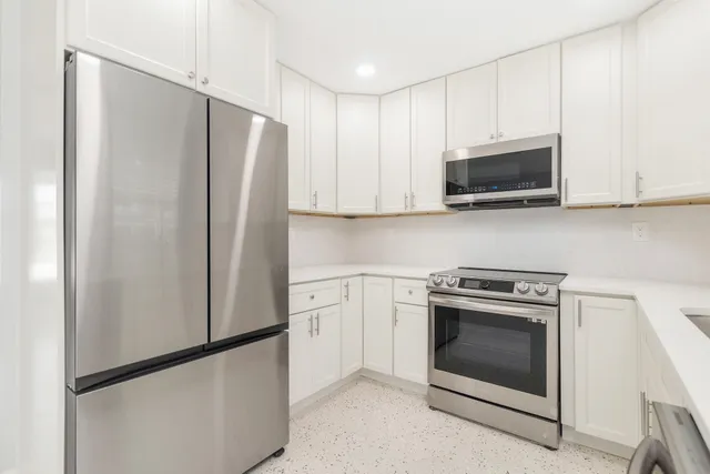 a kitchen with stainless steel appliances white cabinets white stove a microwave and a refrigerator