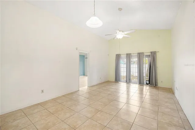 a view of an empty room and kitchen view with wooden floor