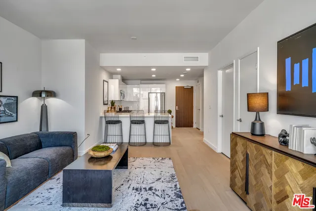 a living room with furniture a rug and kitchen view