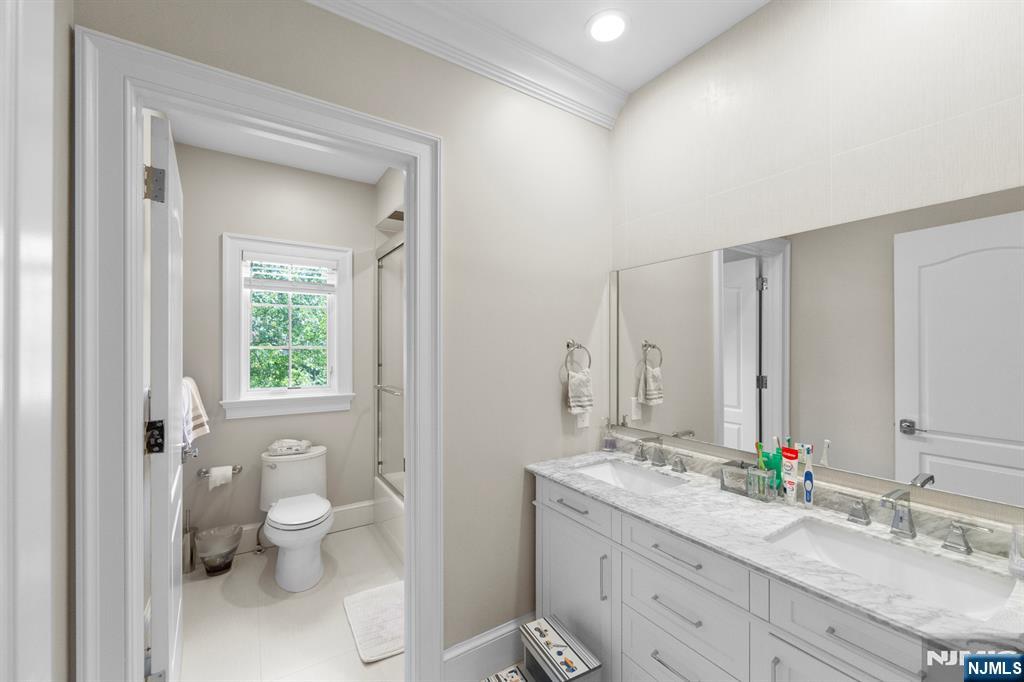 199 Whitman Street Haworth, NJ 07641 - Photo 35 of 50 a bathroom with a granite countertop toilet a sink and a mirror