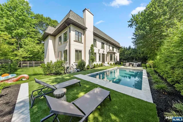 a view of a backyard with lawn chairs and a large tree