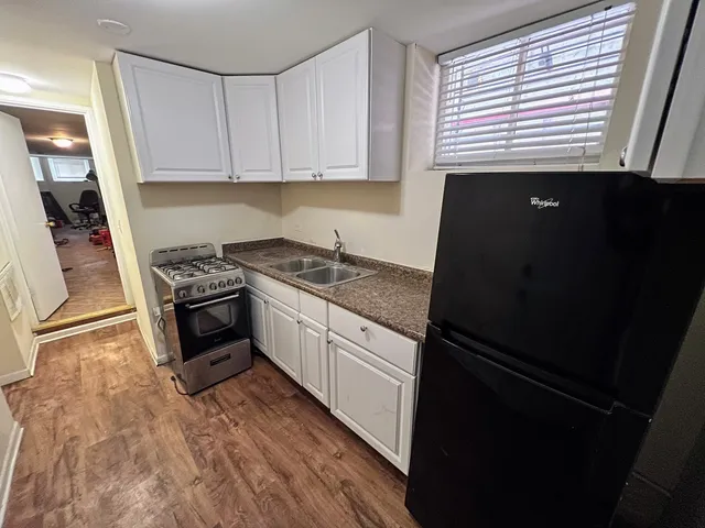 a kitchen with granite countertop stainless steel appliances a refrigerator a sink and white cabinets