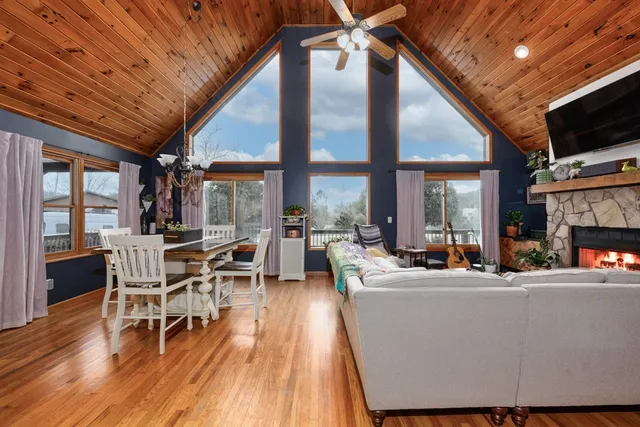 a living room with furniture a large window a dining table and chairs with wooden floor