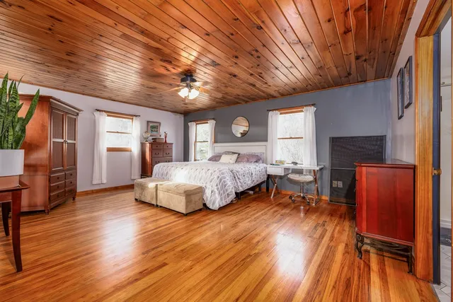 a spacious bedroom with a bed and wooden floor
