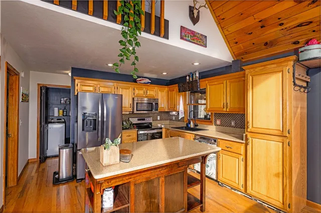 a kitchen with stainless steel appliances granite countertop sink refrigerator dining table and chairs