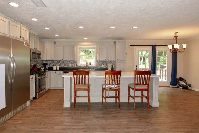 a kitchen with granite countertop a refrigerator and chairs