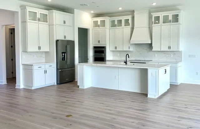 a large kitchen with stainless steel appliances granite countertop a refrigerator and a sink