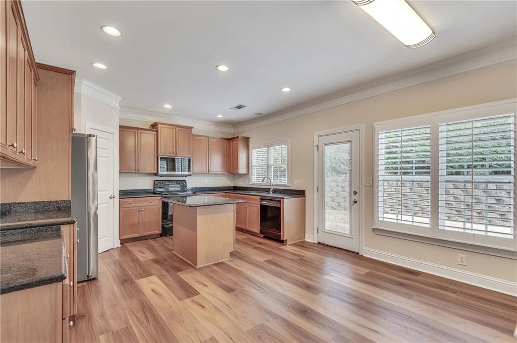 4115 Montvale Crossing Cumming, GA 30041 - Photo 18 of 38 a kitchen with stainless steel appliances granite countertop a refrigerator a sink dishwasher a stove and white countertops with wooden floor