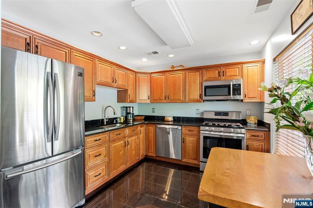 2063 Drake Court Mahwah, NJ 07430 - Photo 11 of 25 a kitchen with stainless steel appliances granite countertop a stove top oven a sink dishwasher a refrigerator and a fireplace with wooden floor