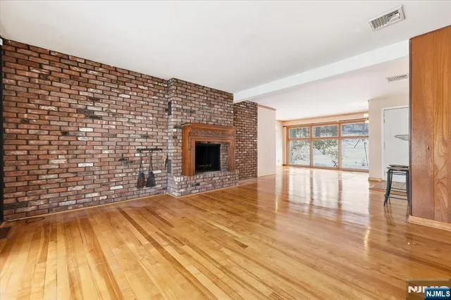 a view of empty room with wooden floor and fireplace