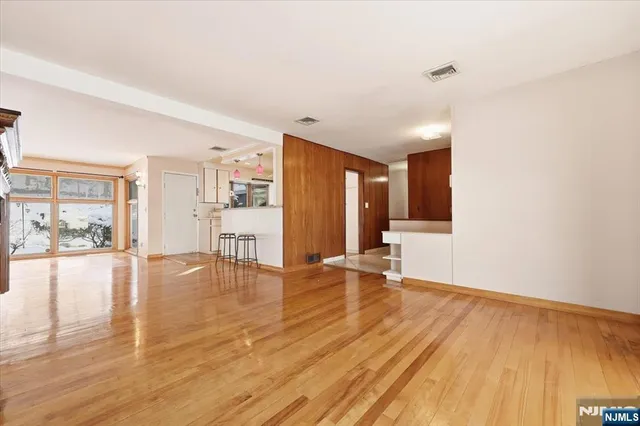 a view of an empty room with wooden floor and a fireplace