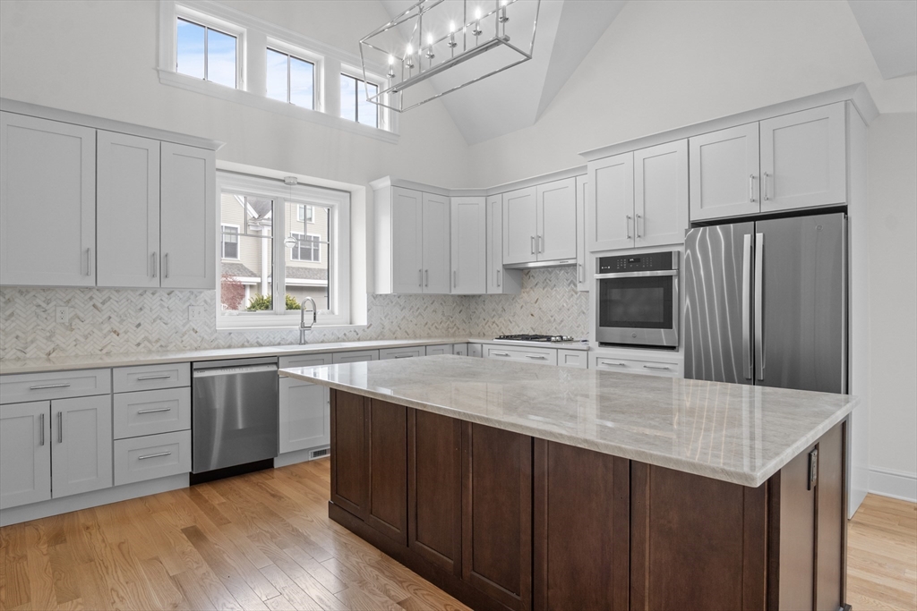 10 Deer Path Lane, Unit 10 Reading, MA 01867 - Photo 5 of 23 a kitchen with stainless steel appliances a sink a stove a refrigerator cabinets and a center island