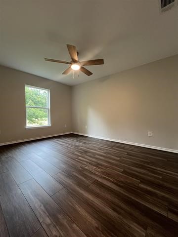 10516 Peck Road Lumberton, TX 77657 - Photo 24 of 27 an empty room with wooden floor chandelier fan and windows