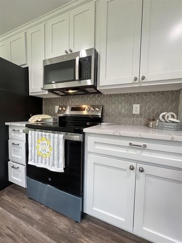 10516 Peck Road Lumberton, TX 77657 - Photo 7 of 27 a kitchen with granite countertop white cabinets stainless steel appliances and wooden floor