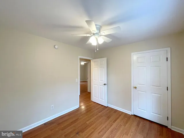 an empty room with wooden floor and a ceiling fan
