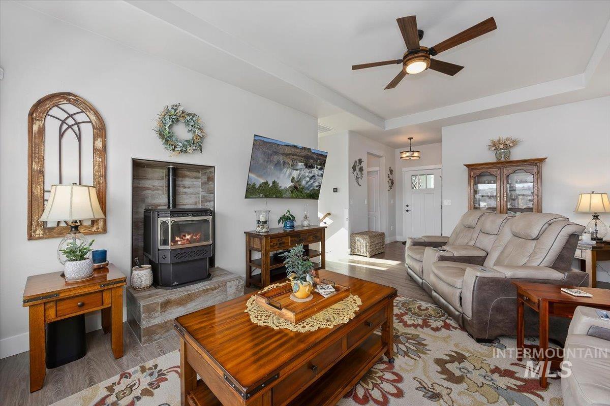 40 Bell Rapids Road Hagerman, ID 83332 - Photo 5 of 50 Living area with a wood stove, light wood-style flooring, ceiling fan, and a raised ceiling