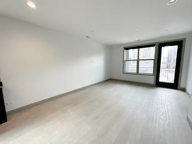 a view of an empty room with window and chandelier fan