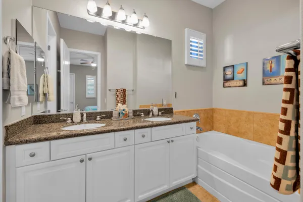 a bathroom with a granite countertop sink a mirror a and a bathtub