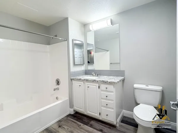 a bathroom with a granite countertop toilet sink and a bathtub