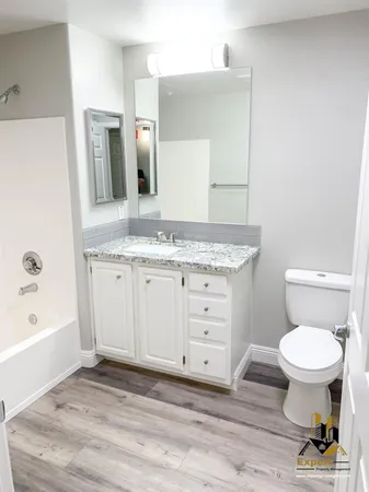 a bathroom with a granite countertop toilet sink and mirror