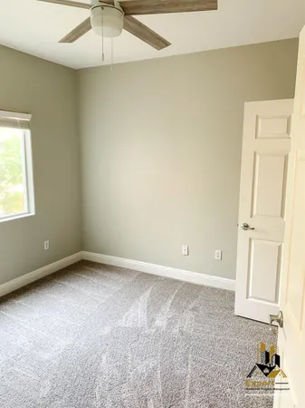 an empty room with a window and a ceiling fan