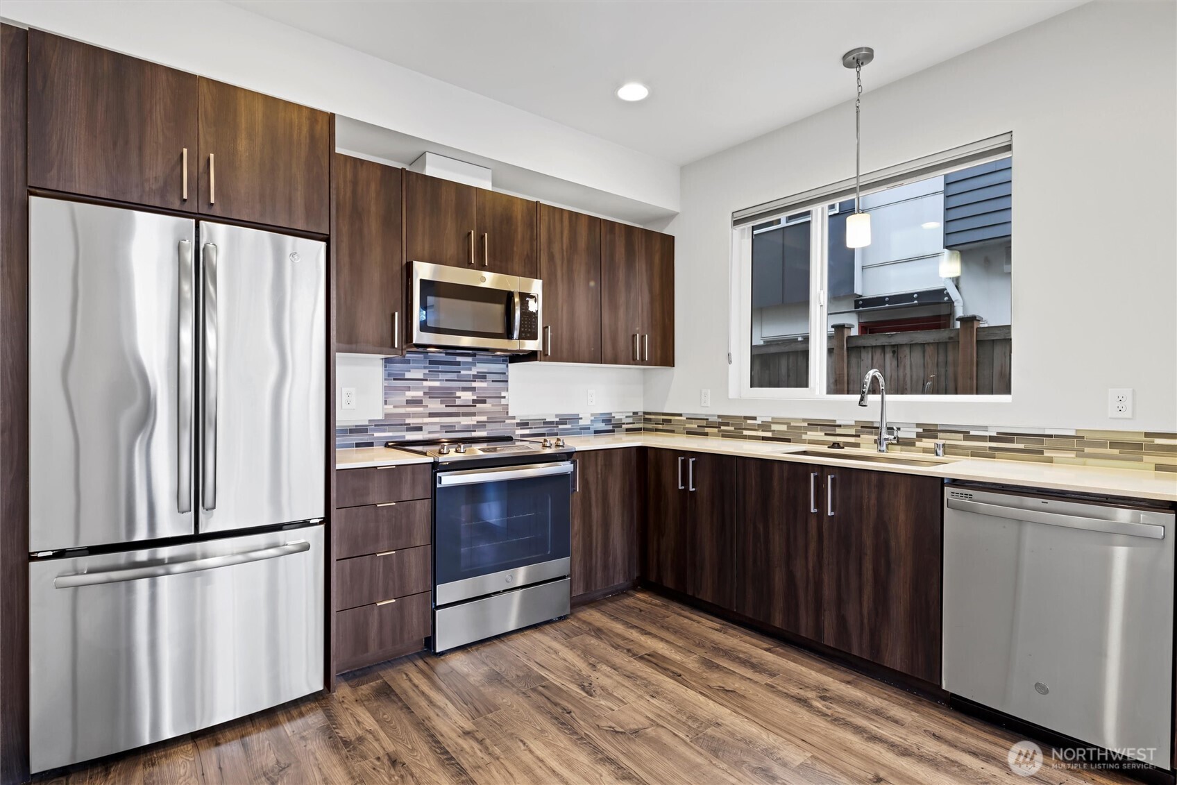 6917 Carleton Avenue South, Unit B Seattle, WA 98108 - Photo 8 of 25 a kitchen with granite countertop stainless steel appliances a refrigerator cabinets and wooden floor