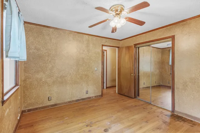 wooden floor in an empty room with a chandelier fan