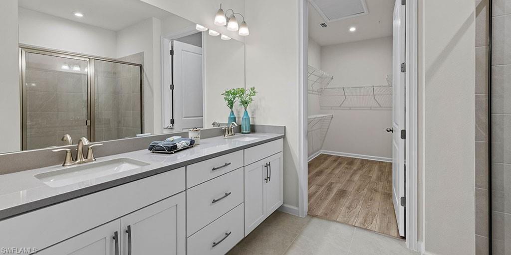 4653 Arboretum Circle, Unit 104 Naples, FL 34112 - Photo 14 of 21 a bathroom with a double vanity sink and a mirror