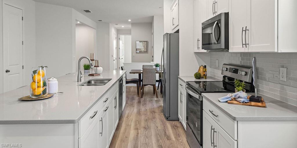 4653 Arboretum Circle, Unit 104 Naples, FL 34112 - Photo 6 of 21 a kitchen with a sink appliances and cabinets