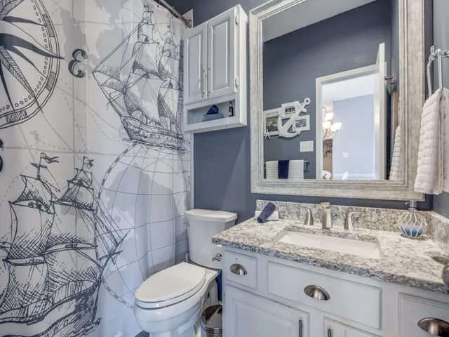 a bathroom with a granite countertop toilet sink and mirror