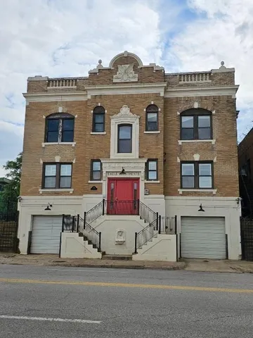 a view of a brick building next to a yard with big trees