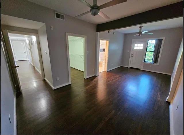 a view of empty room with wooden floor and fan