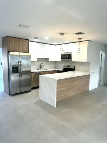 a large kitchen with kitchen island a sink stainless steel appliances and cabinets