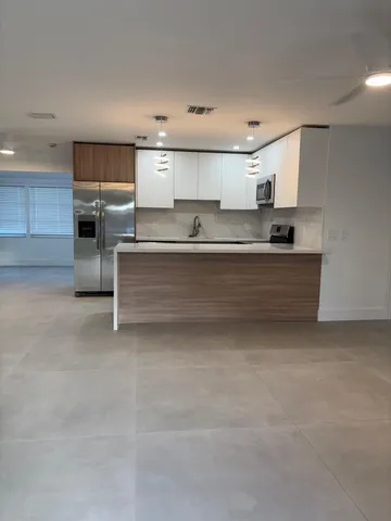 a kitchen with kitchen island granite countertop stainless steel appliances a stove and a chandelier