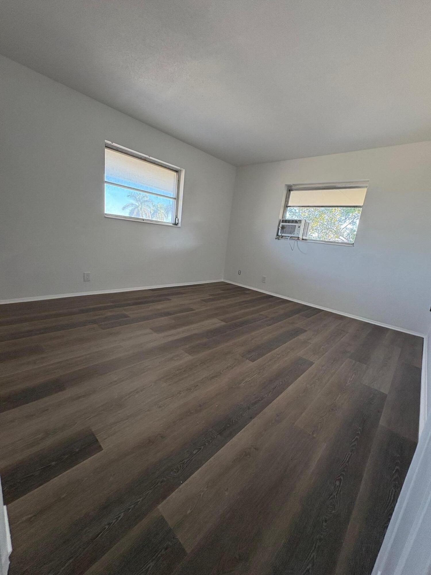 1150 East Sample Road, Unit 312 Pompano Beach, FL 33064 - Photo 5 of 11 an empty room with wooden floor and windows