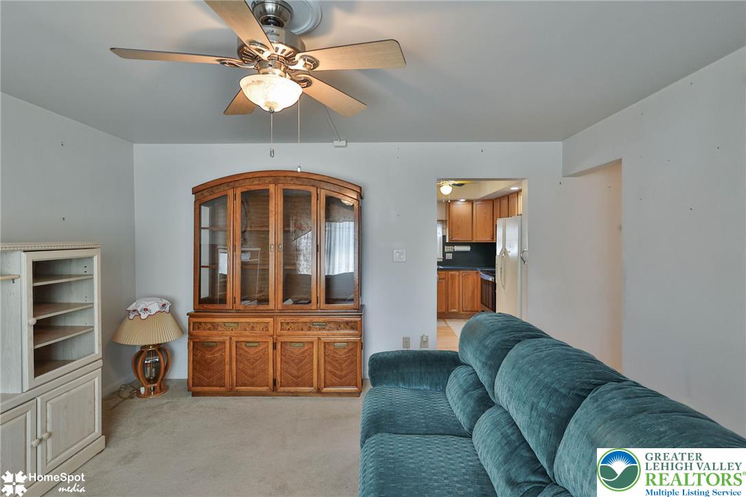 3069 Shakespeare Road Bethlehem, PA 18017 - Photo 4 of 50 A living space offers carpet flooring and a ceiling fan, with a glimpse into the kitchen.