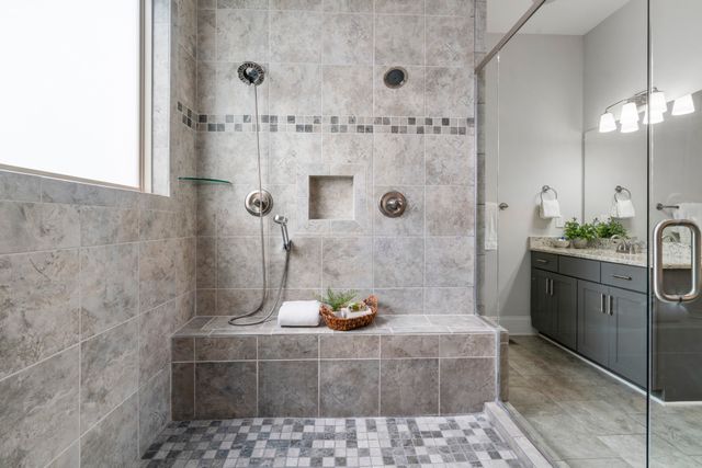 a bathroom with a granite countertop shower a sink and vanity