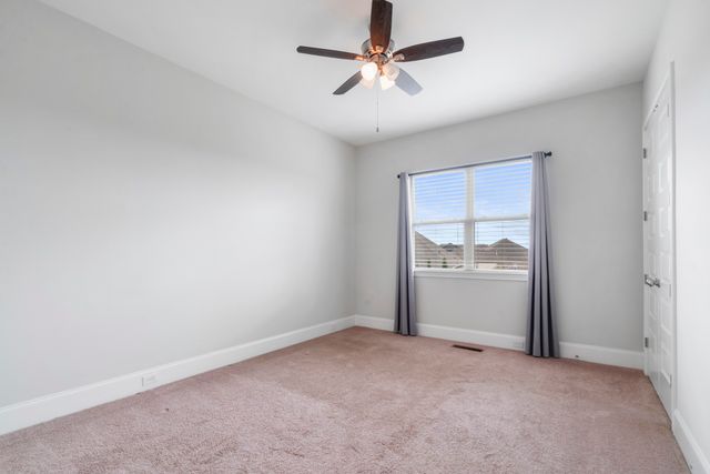 an empty room with windows and ceiling fan