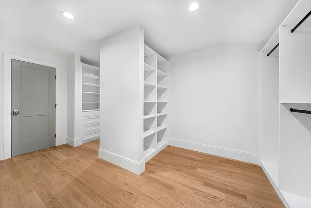 a view of an empty room with wooden floor and closet