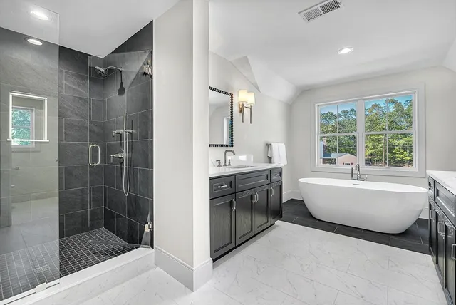 a bathroom with a bathtub a sink a window and a shower