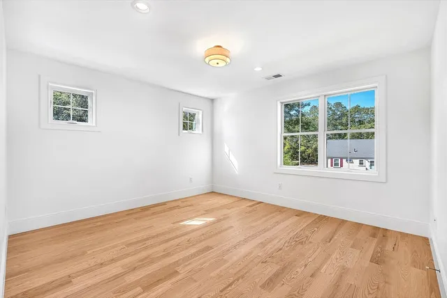 a view of empty room with wooden floor and window