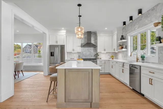 a large kitchen with stainless steel appliances granite countertop a stove a sink dishwasher and a refrigerator with wooden floor