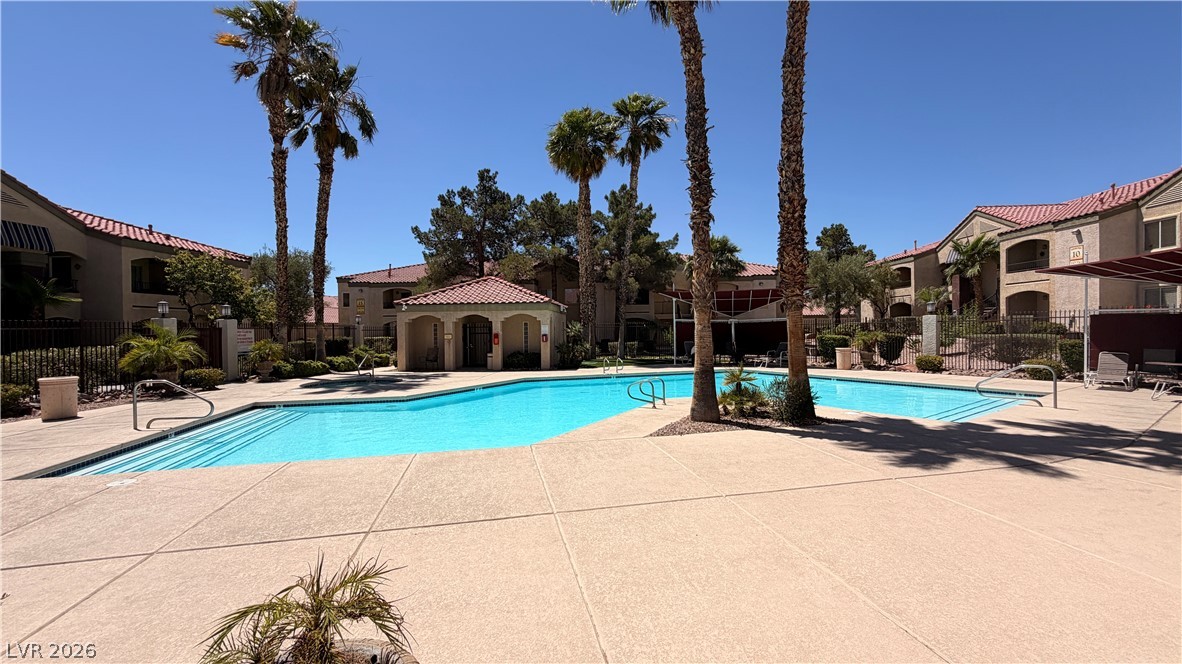 7885 West Flamingo Road, Unit 1131 Las Vegas, NV 89147 - Photo 6 of 36 An inviting community pool awaits, framed by graceful palm trees and residential structures.