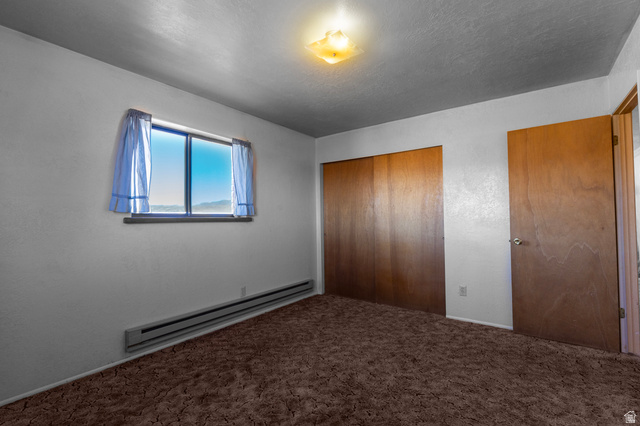 1208 East Tidwell Road Loa, UT 84747 - Photo 27 of 40 Unfurnished bedroom featuring a baseboard radiator, a closet, a textured ceiling, and carpet