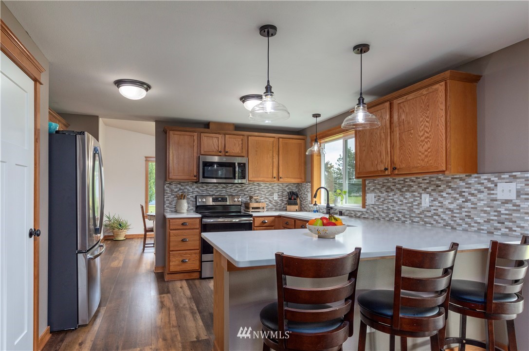 6519 190th Trail Southwest Rochester, WA 98579 - Photo 13 of 40 a kitchen with stainless steel appliances granite countertop a stove a refrigerator a kitchen island a sink dishwasher a dining table and chairs with wooden floor