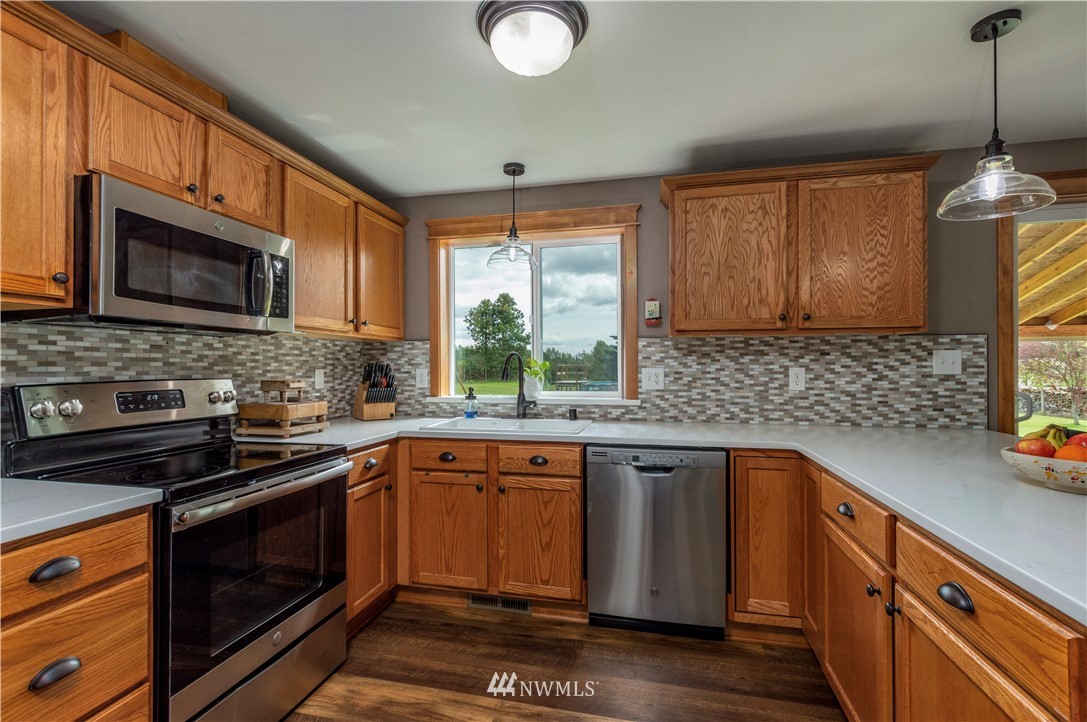 6519 190th Trail Southwest Rochester, WA 98579 - Photo 15 of 40 a kitchen with stainless steel appliances granite countertop wooden cabinets stove top oven and sink