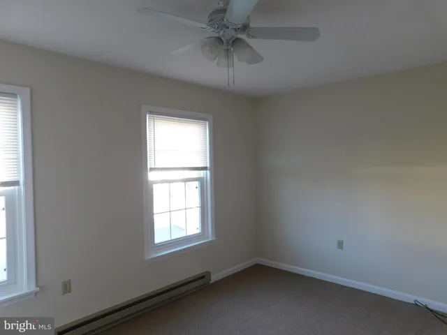 an empty room with a window and a ceiling fan