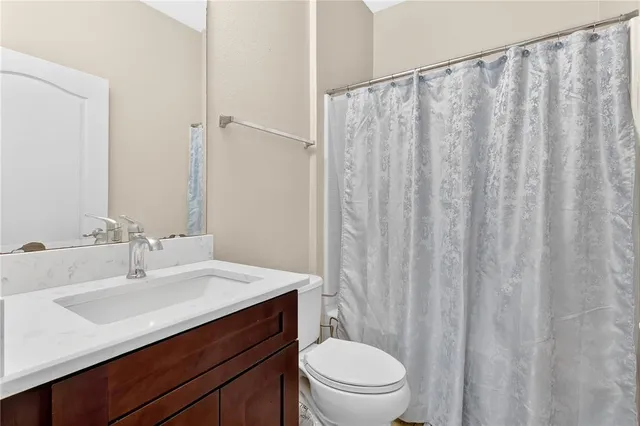 a bathroom with a sink a toilet a mirror and shower curtain