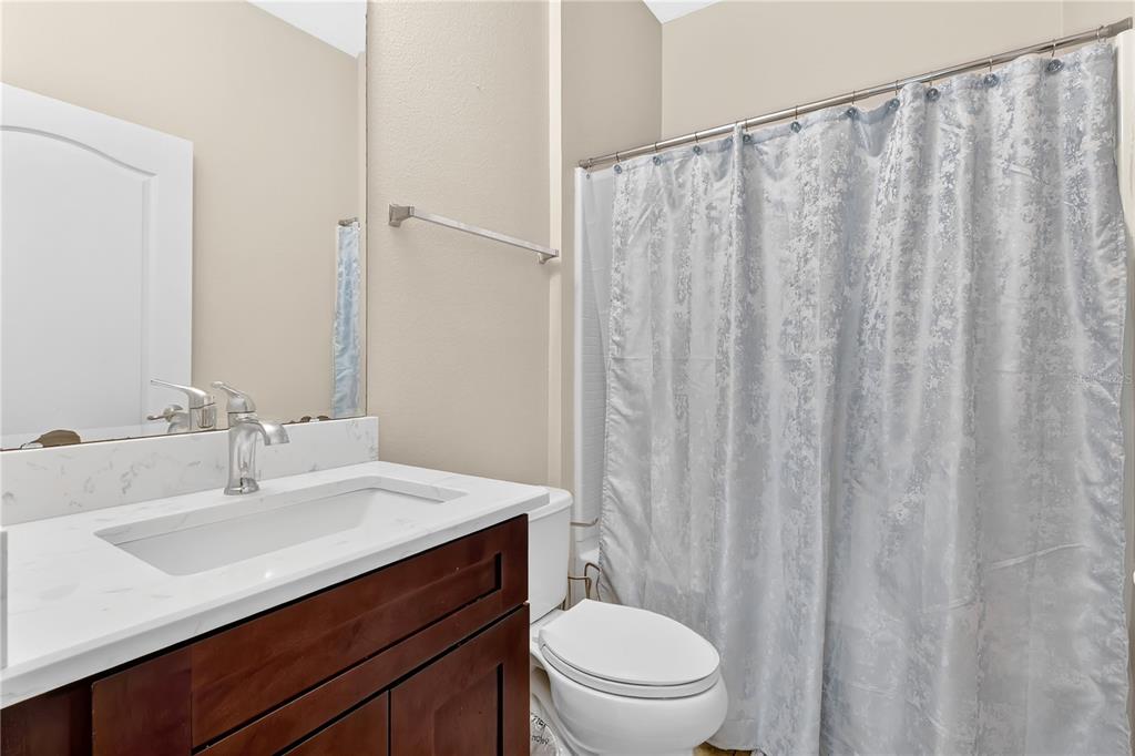 1938 Commander Way Kissimmee, FL 34746 - Photo 15 of 30 a bathroom with a sink a toilet a mirror and shower curtain