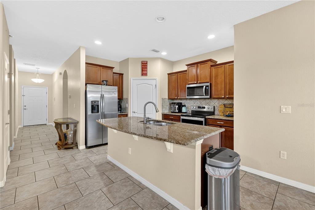 1938 Commander Way Kissimmee, FL 34746 - Photo 6 of 30 a kitchen with stainless steel appliances granite countertop a refrigerator a stove a sink and a microwave